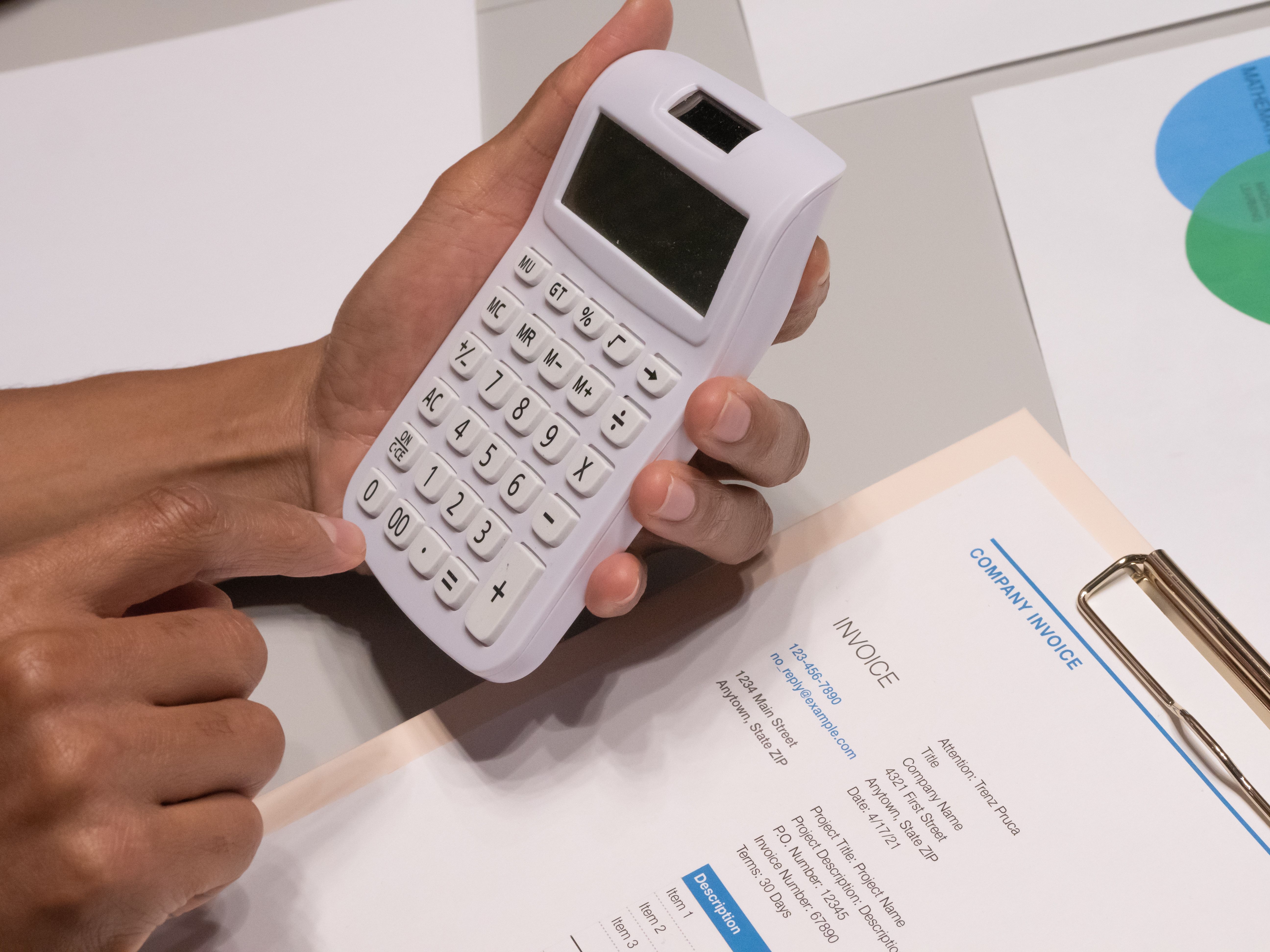 Hands using a calculator beside an invoice, representing court costs and legal fees.