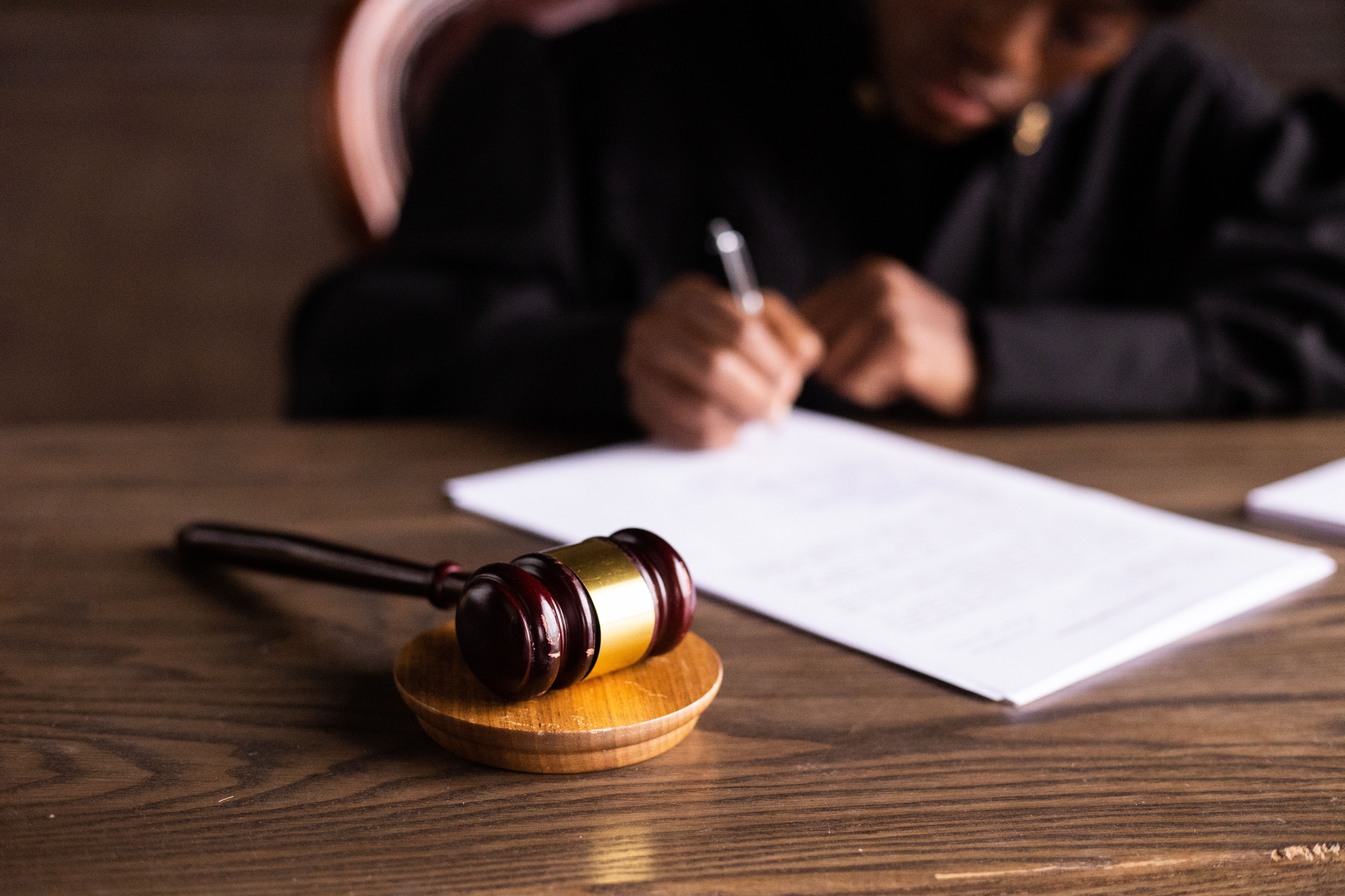 Judge signing class action settlement documents at a desk with a gavel