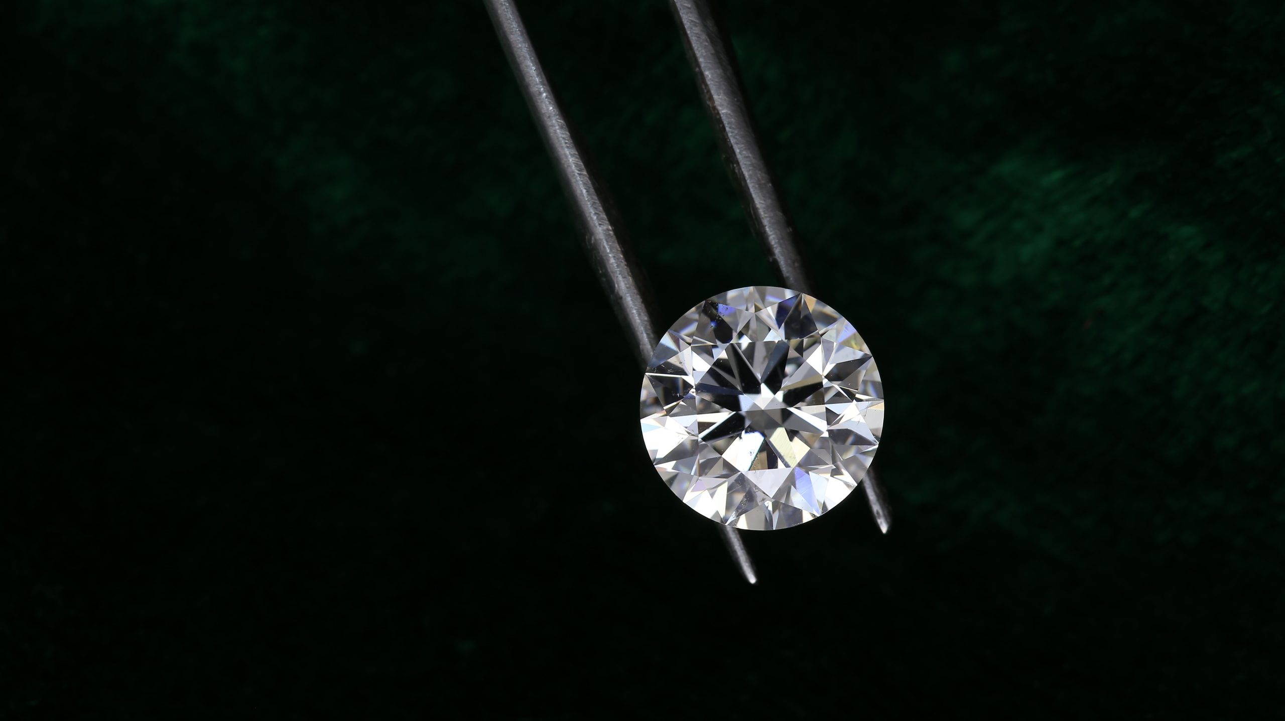 Loose diamond held in tweezers for examining its cut and clarity, illustrating how lab-grown diamonds are assessed.