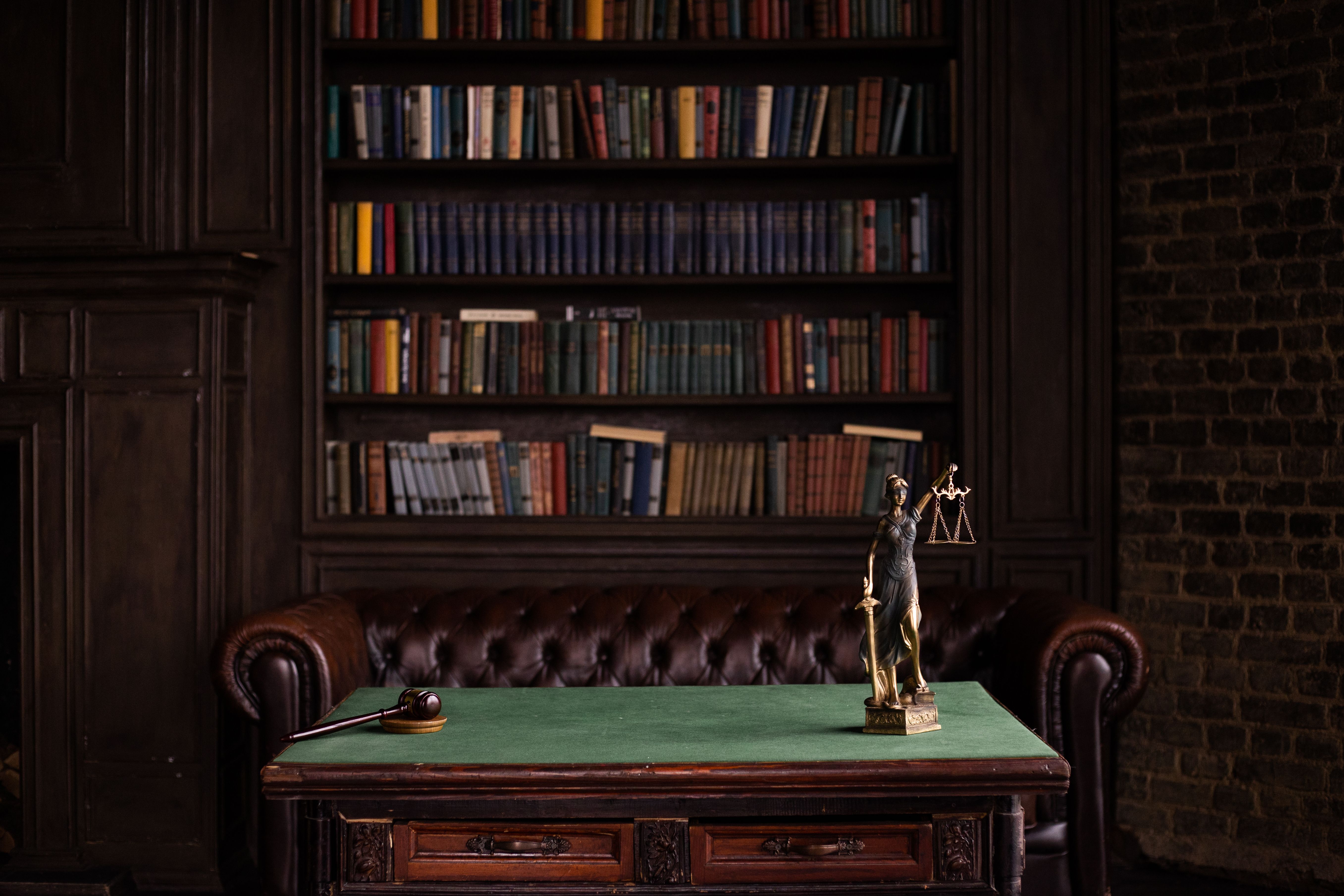 Law study room with books, a gavel, and a Lady Justice figurine on a green table