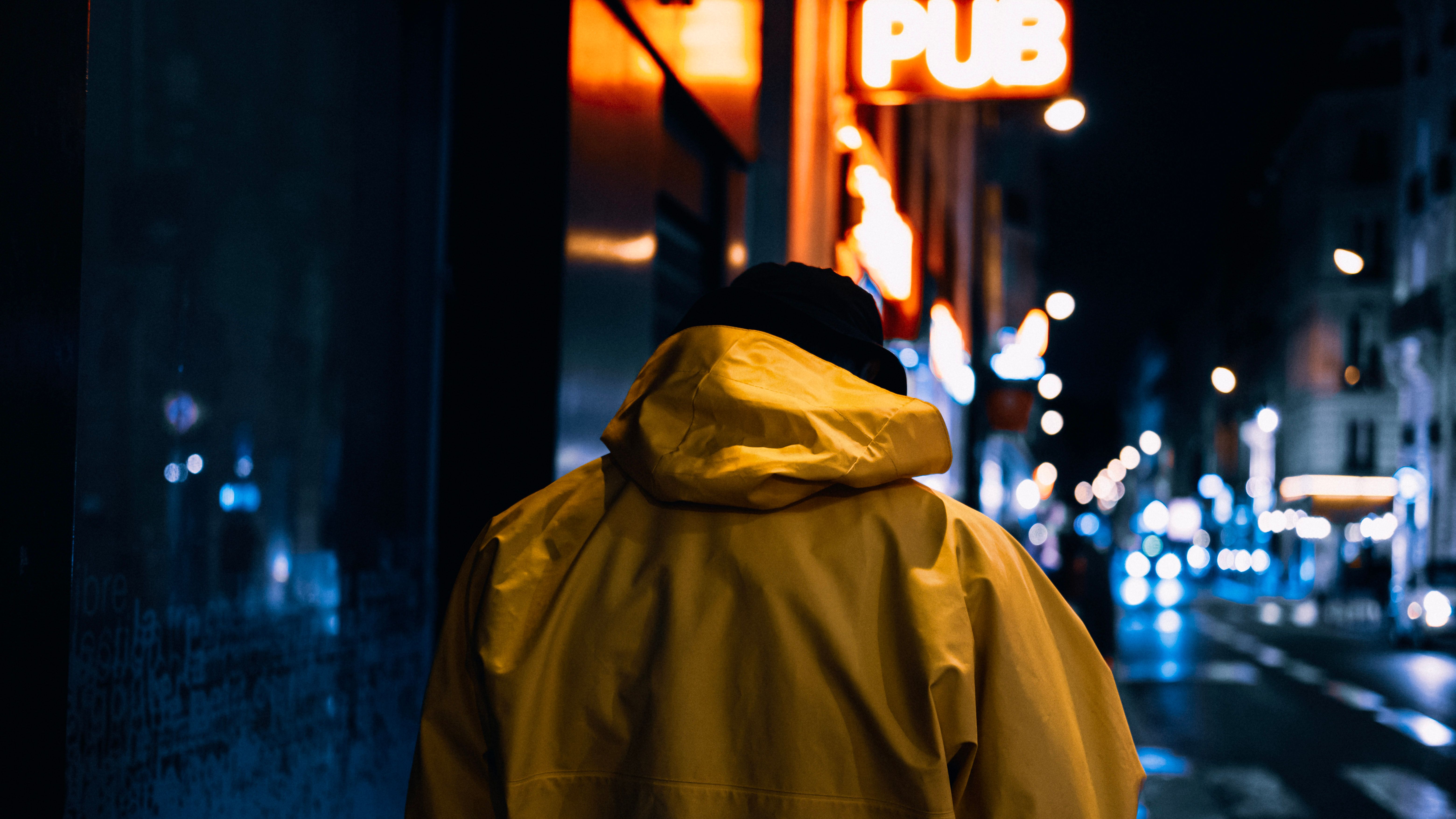 Person walking through a neon-lit city street at night, evoking urban loneliness and the search for connection.