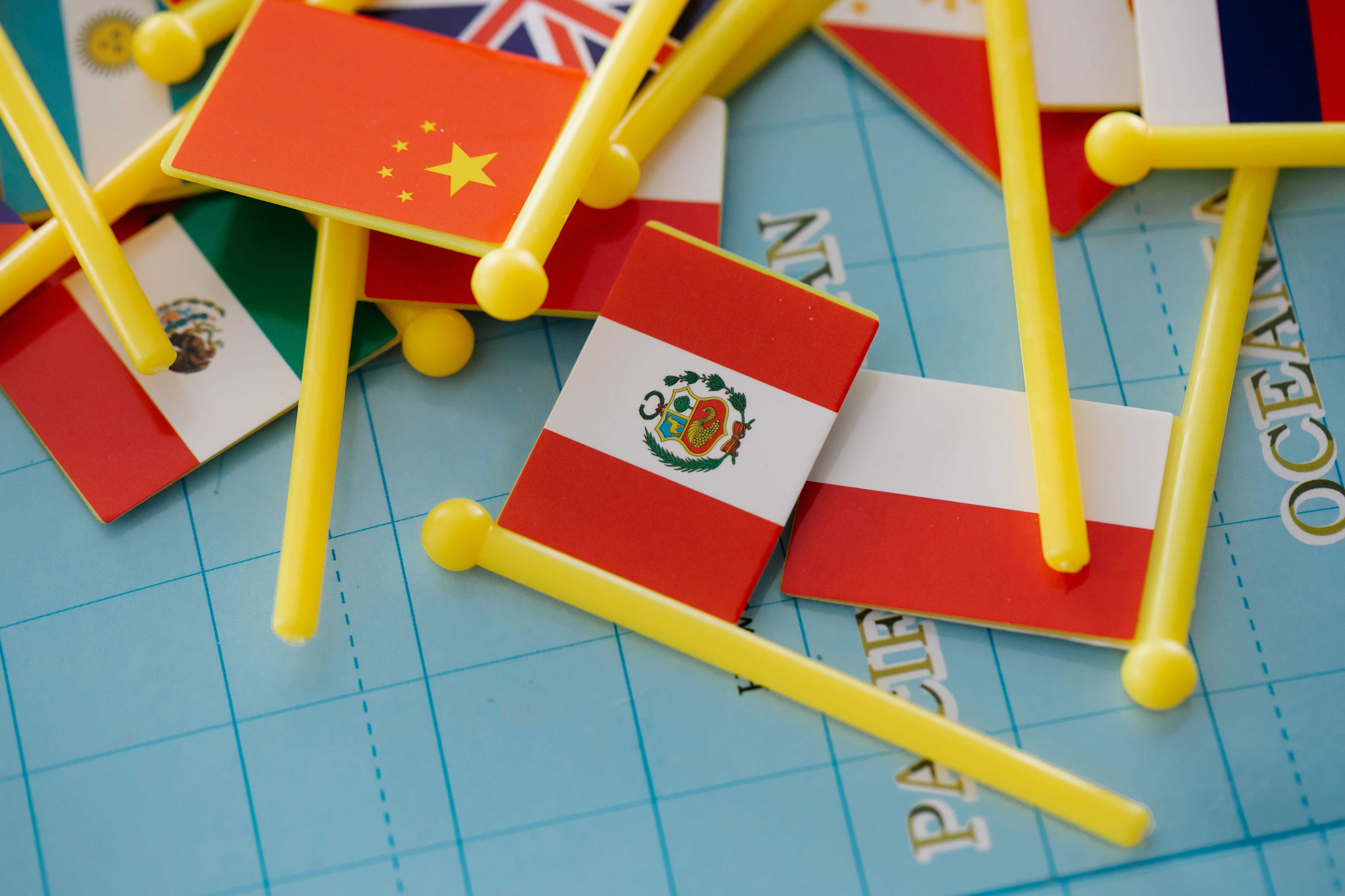 Collection of miniature national flags placed on a world map representing global relations between countries